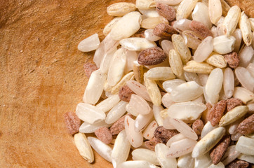 Mix of different rice types rose, wild, brown, arborio in the wooden spoon. Closeup macro shot.