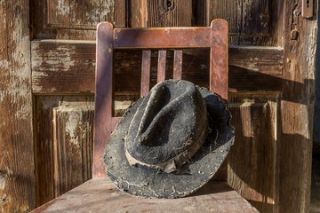 Battered old hat damaged by clothes moth on vintage background. A forgotten hat covered with spider web among the ruins of a house. Imagine the owner of this hat and tell their story.