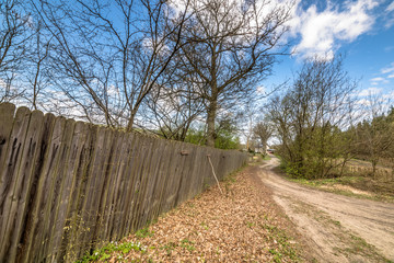 Rural road and wooden fence, spring landscape