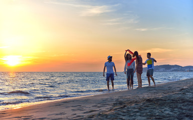 Fototapeta premium group of happy young people dancing at the beach on beautiful summer sunset