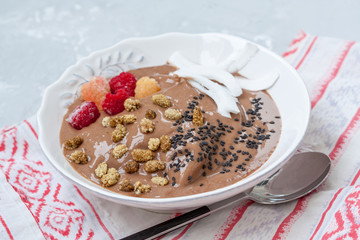 Chocolate smoothie bowl of oatmeal, sesame seeds and raspberries for breakfast. Love for a healthy raw food concept.