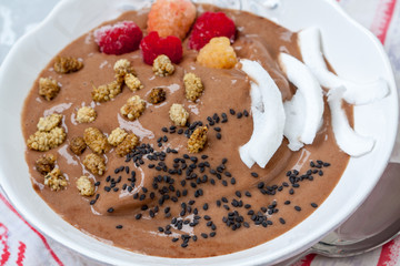 Chocolate smoothie bowl of oatmeal, sesame seeds and raspberries for breakfast. Love for a healthy raw food concept.