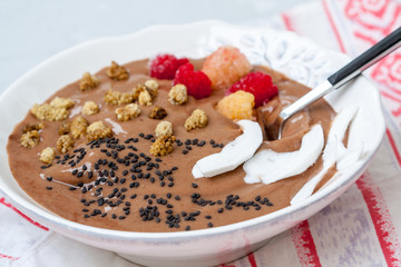 Chocolate smoothie bowl of oatmeal, sesame seeds and raspberries for breakfast. Love for a healthy raw food concept.