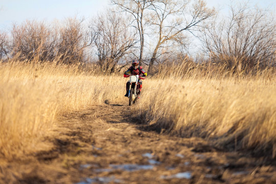 Enduro bike rider on a field with dry grass in autumn