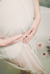 beautiful pregnant woman in a bathroom with milk and flowers