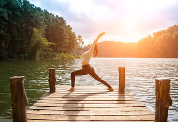 Healthy woman practicing yoga on the bridge in the nature