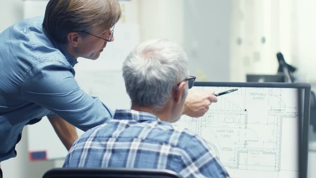 Two Senior Architectural Engineers Working With Building Plan on a Personal Computer. They Actively Discuss Various Plans and Schemes.  Shot on RED Cinema Camera in 4K (UHD). 