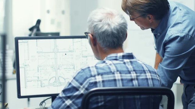 Two Senior Architectural Engineers Working With Building Blueprint on a Personal Computer. They Actively Discuss Various Plans and Schemes.  Shot on RED Cinema Camera in 4K (UHD). 