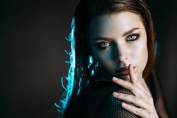 Fashion model beautiful girl in fashionable clothes in ultraviolet light, showing different poses. Beauty body and face. Photos shot in studio. Advertising Space
