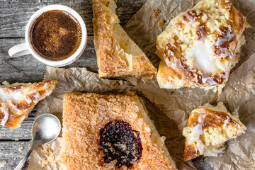 Fattening food breakfast - french pastry, sweet bun and coffee cup on wooden table, flat lay overhead