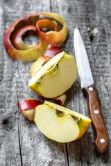 Two apple quarters with peeled peel on rustic table
