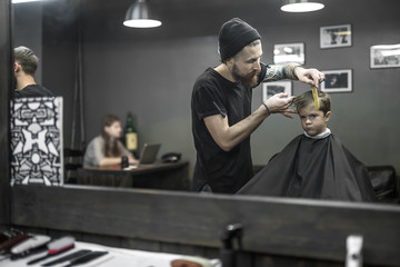 Fototapeta na wymiar Haircut of small boy in barbershop