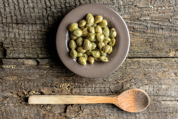 Marinated capers, italian cooking ingredients on wooden table