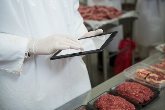 Mid section of butcher maintaining records over digital tablet - Powered by Adobe