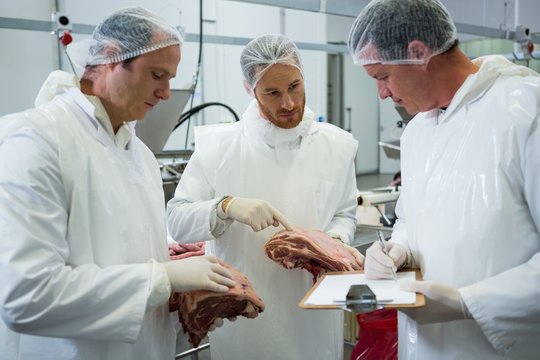 Butchers maintaining records on clipboard