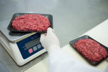 Butcher weighing packages of minced meat