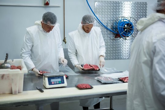 Butchers weighing packages of meat - Powered by Adobe