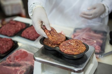 Butcher weighing meat patties on scale