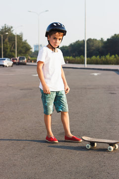 Boy stands with a skateboard outdoors
