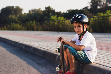 Boy sits with a skateboard outdoors