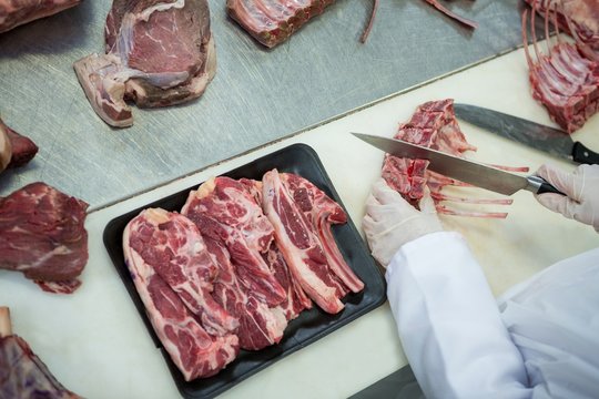 Butcher cutting meat at meat factory