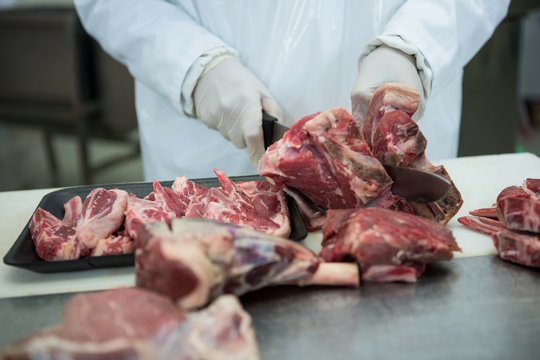 Butcher cutting meat at meat factory