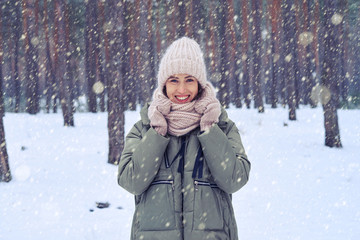 Fototapeta premium Charming young woman in pink knitted mittens, cap and scarf posi