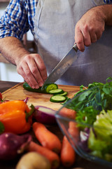 Crop shot of hands slicing cucumber on cutting board
