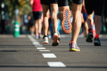 Course de marathon, les pieds des gens sur la route de la ville