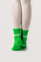 Female legs in white stockings and green knitted socks.