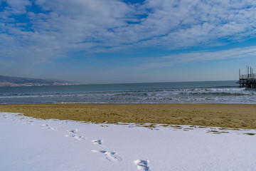 Snowy beach and sea at winter with blue sky