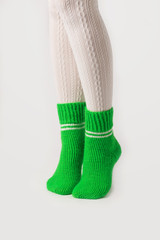 Female legs in white stockings and green knitted socks.