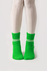 Female legs in white stockings and green knitted socks.