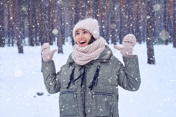 Surprised woman having fun while catching snowflakes in winter