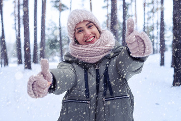 Thumbs up of a jubilant girl in the winter forest