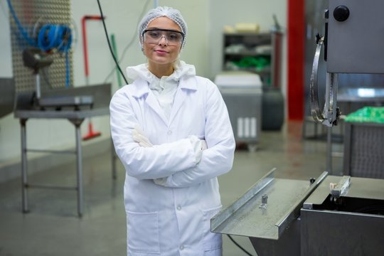 Female technician standing with arms crossed at meat factory