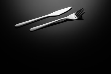 Black food background. Stainless steel, modern silverware on black background with reflection. Image with copy space. Symbol or concept for diners, cafes and good food competitions and festivals