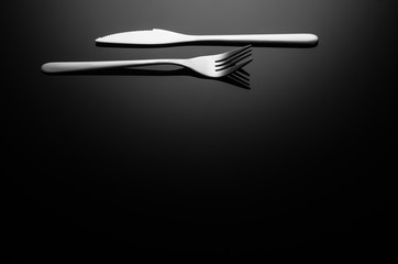 Fototapeta na wymiar Black food background. Stainless steel, modern silverware on black background with reflection. Image with copy space. Symbol or concept for diners, cafes and good food competitions and festivals