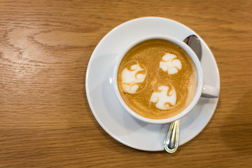 A cup of Latte art on wooden bar