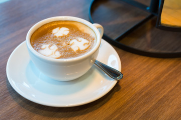 A cup of Latte art on wooden bar