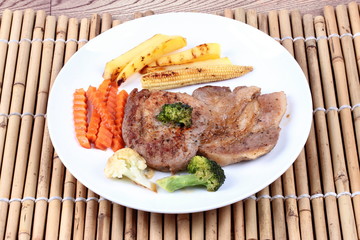 Pork steak with mixed vegetable on white dish.