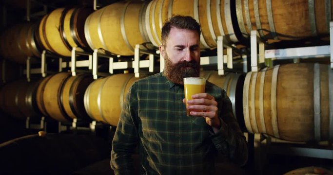 a brewmaster expert checks the quality of the freshly tapped beer from wooden barrels formerly used for flavour the wine or beer.