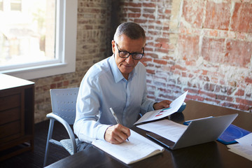 Mature Businessman Working On Laptop In Boardroom