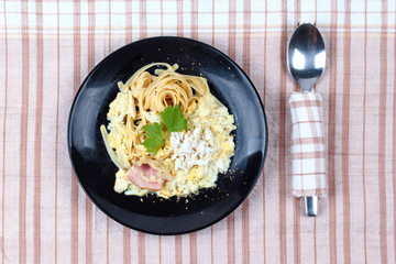 Spaghetti carbonara with crab, black dish.