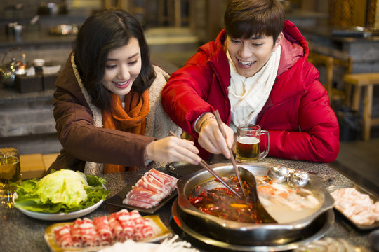 Young couple having dinner in hotpot restaurant