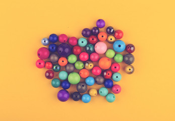 many colored glass pearls beads on yellow background