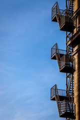 Color picture of emergency iron stairway on a blue sky - 132142679