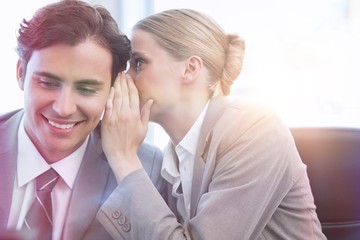 Young businesswoman whispering something to her colleague