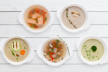 Variation of tasty restaurant hot dishes flat lay. Top view on white wooden table with set of different soups. Worldwide cuisine, healthy food, buffet, lunch, menu concept