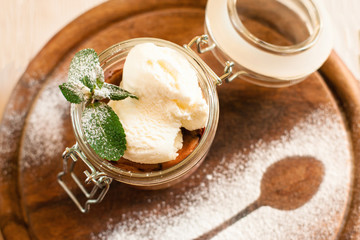Ice cream in glass jar with mint top view. Sweet dessert served on wooden board decorated with sugar powder spoon contour. Restaurant serving, menu, summer concept